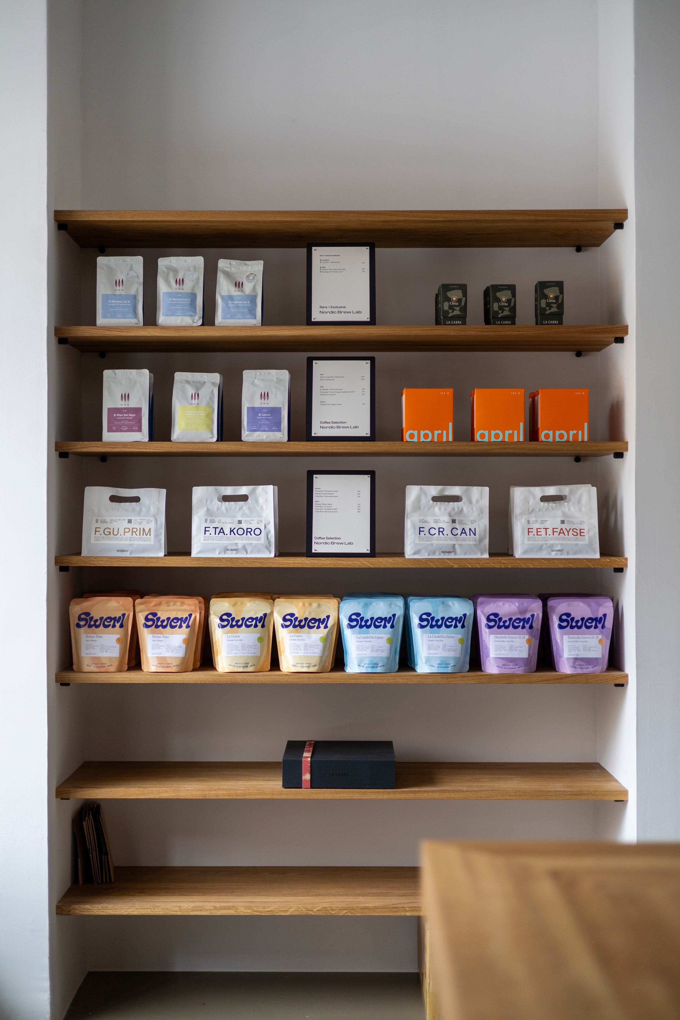 Specialty coffee shelf in Stockholm. Ona Coffee, April Coffee, La Cabra Coffee, Nomad coffee and Swerl coffee placed on wooden shelves.