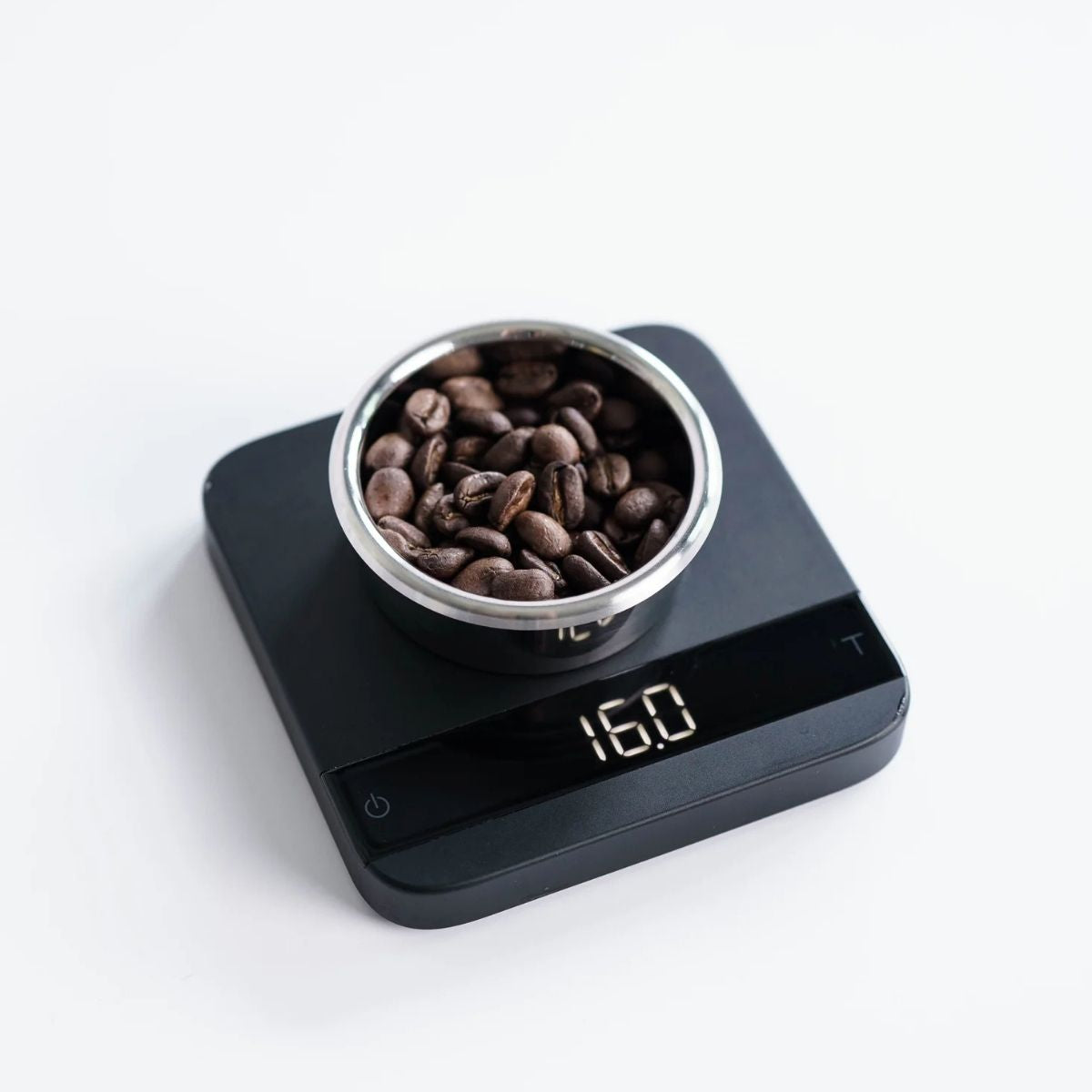 Unibasket Weber Workshops precision espresso basket on digital scale with coffee beans.
