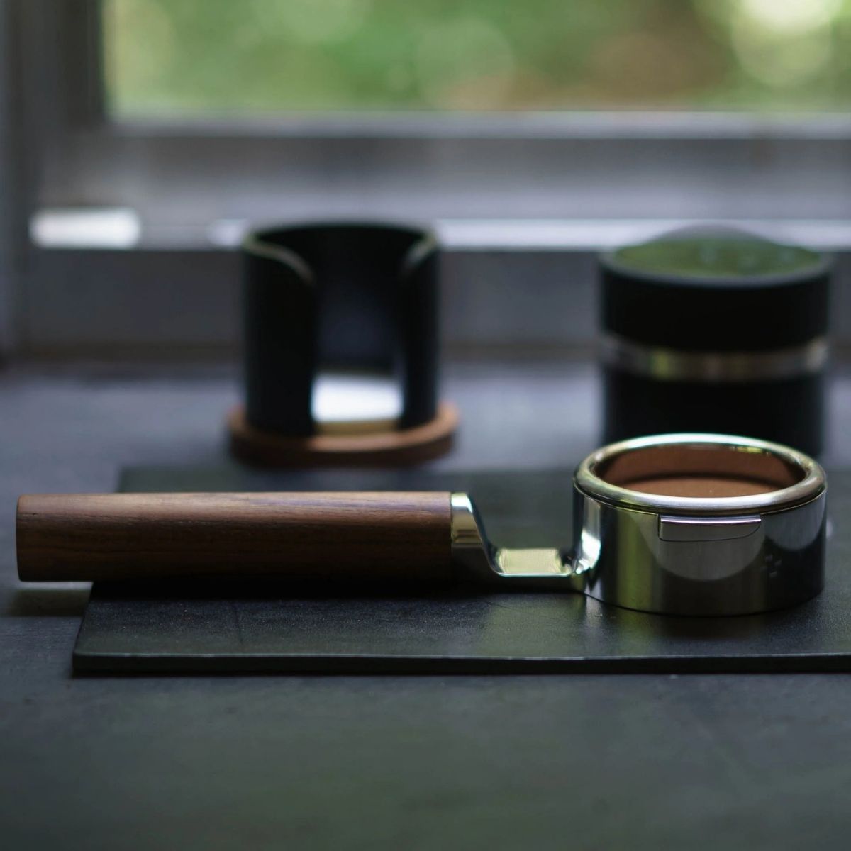 Buck portafilter Weber Workshops on a countertop, showcasing its stainless steel design and wooden handle.