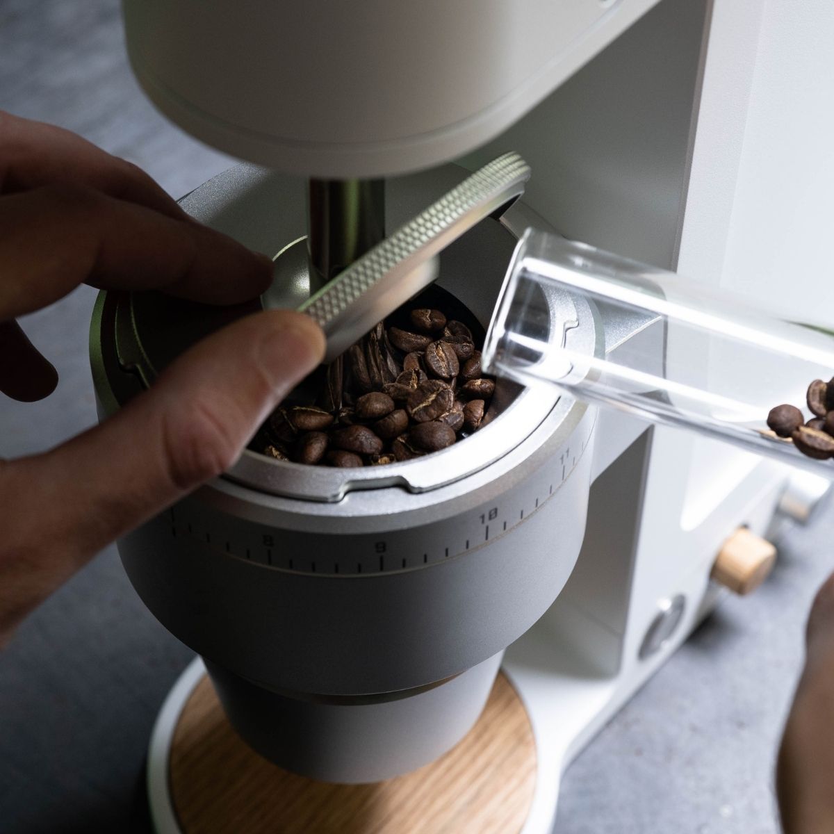 Adding coffee beans into Weber Workshops Key specialty coffee grinder.