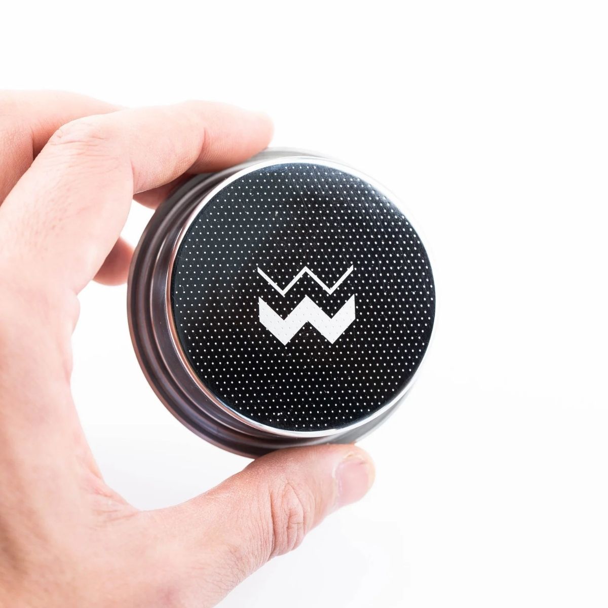 Close-up of a hand holding a Unibasket Weber Workshops precision espresso basket with a logo design.