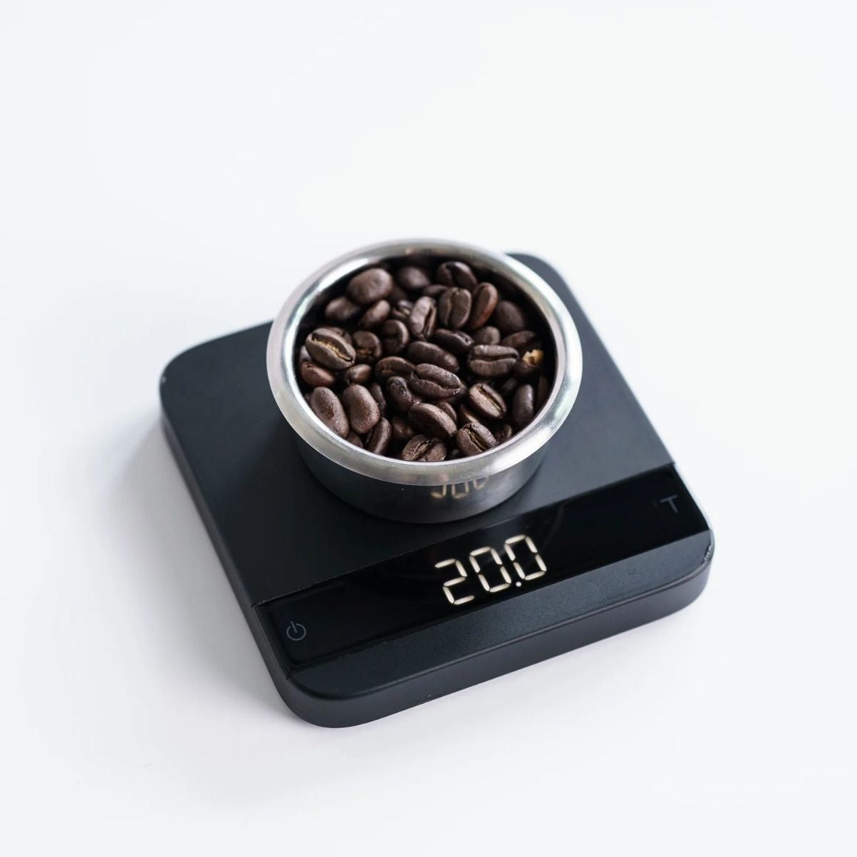 Unibasket Weber Workshops precision espresso basket on a digital scale measuring coffee beans.